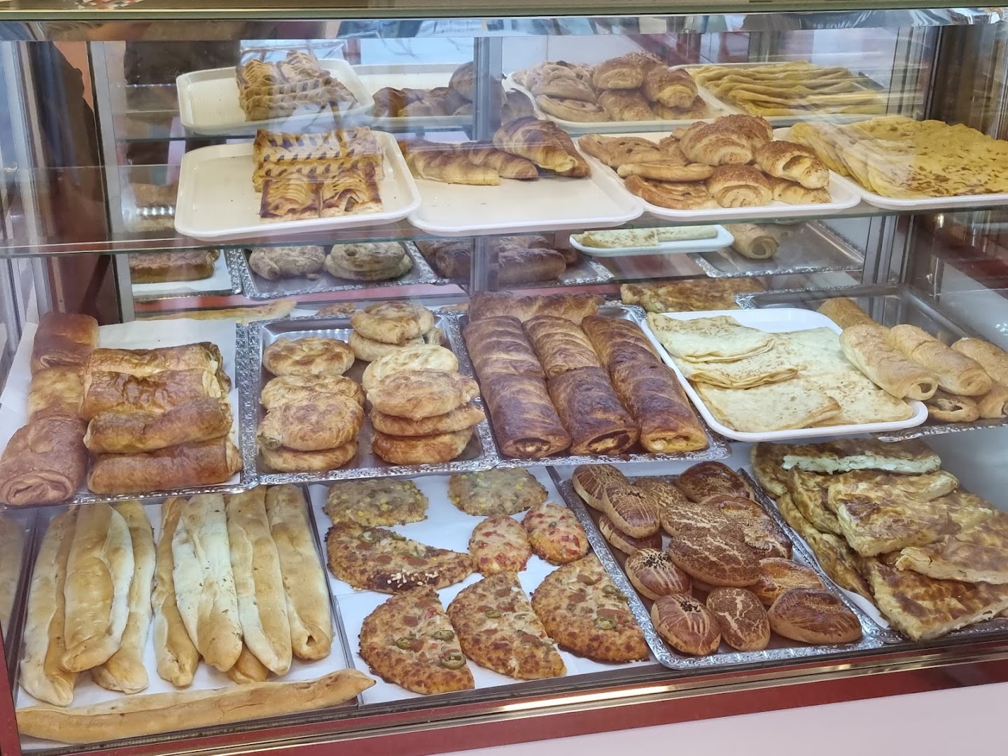 Bakkerijvitrine met börek, gebak en platbrood bij Simit Bakkerij
